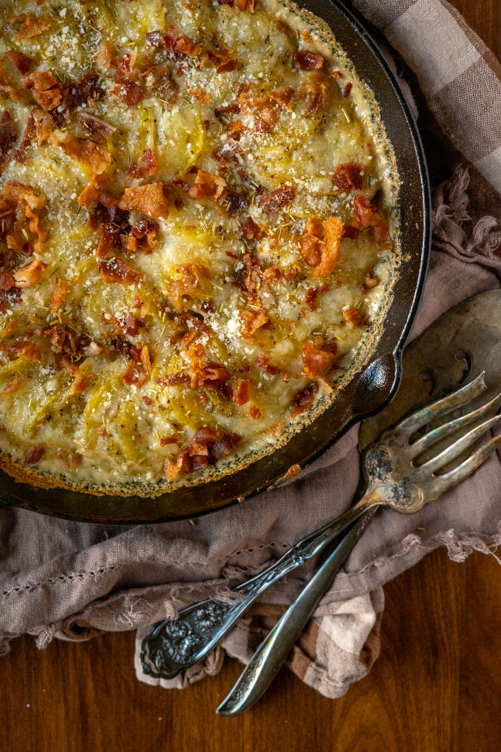 potatoes au gratin in a cast iron pan with vintage silverware.