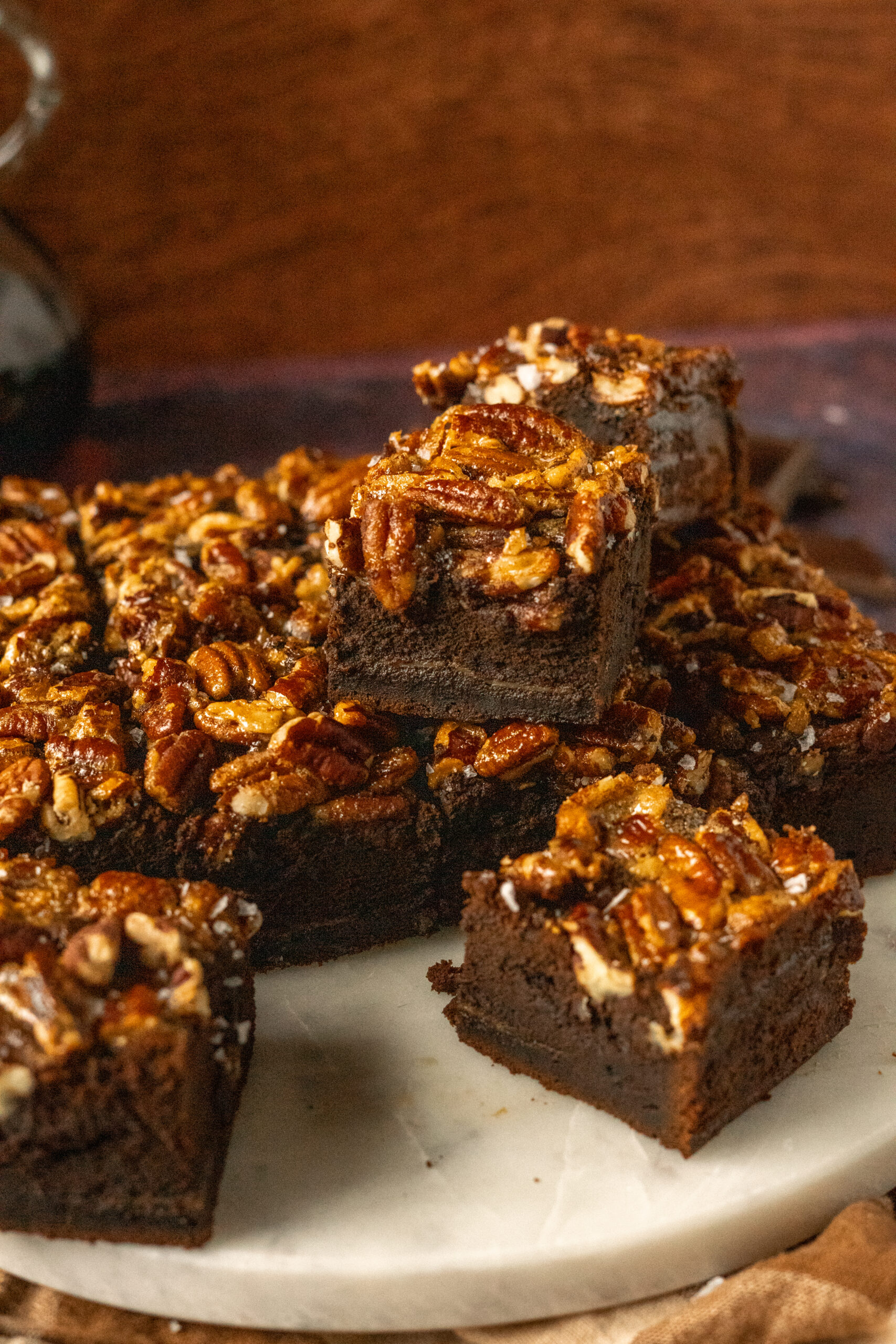 pecan pie brownies sliced and stacked on a white marble slab.