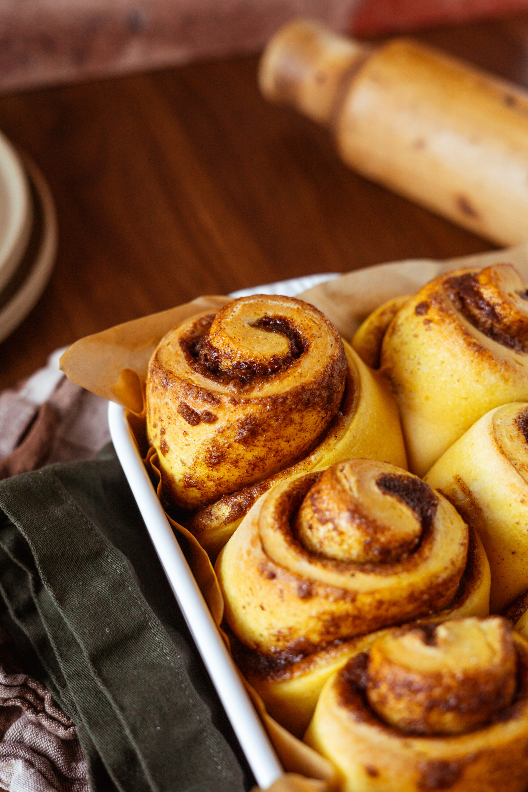 angled view of pumpkin cinnamon rolls in baking dish before frosting.