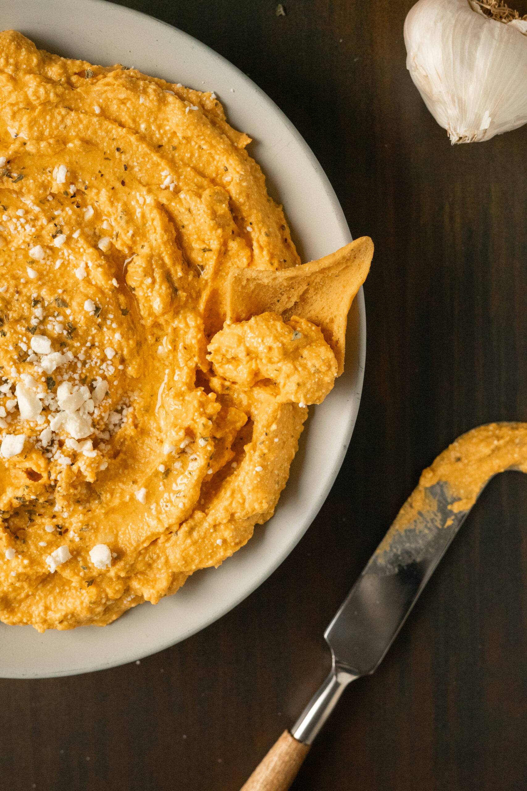 pumpkin feta dip in a beige bowl with a chip in the dip.
