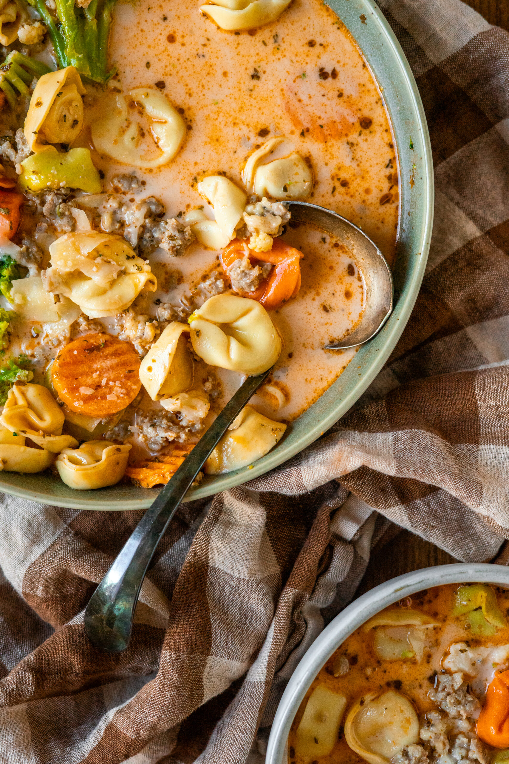 close up overhead shot of tortellini soup with spoon resting in the bowl.