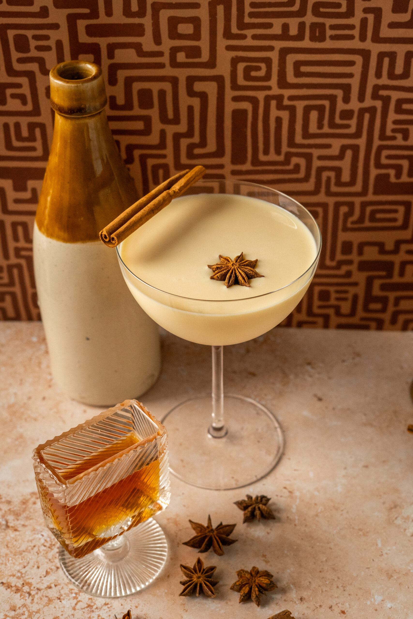 eggnog martini in a coupe glass with garnish on a brown background.
