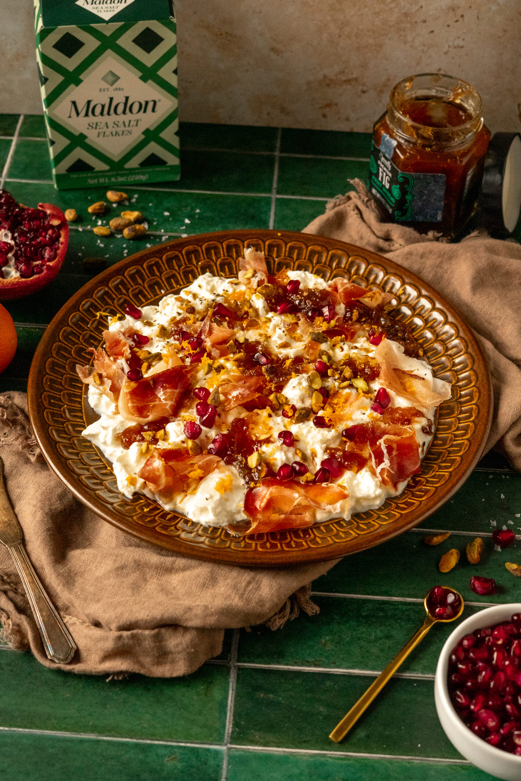 angled view of burrata plate on green tile surface with marble wall in background.