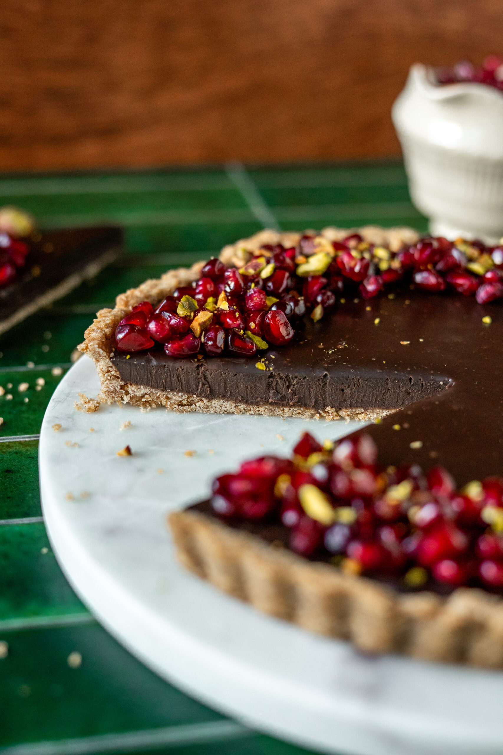 close up of chocolate pomegranate tart with slice taken out.
