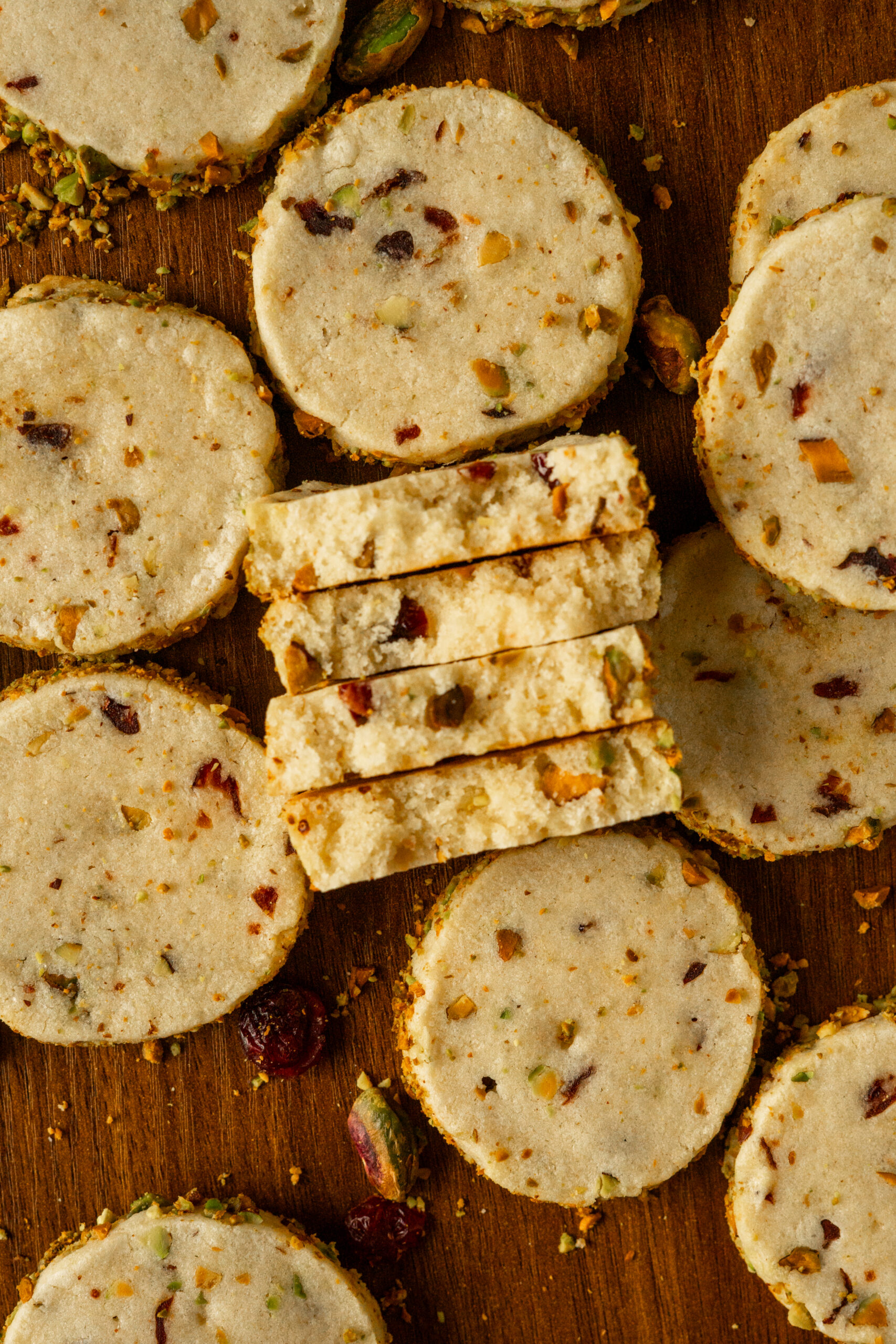 pistachio cranberry cookies sliced and stacked on wooden table.