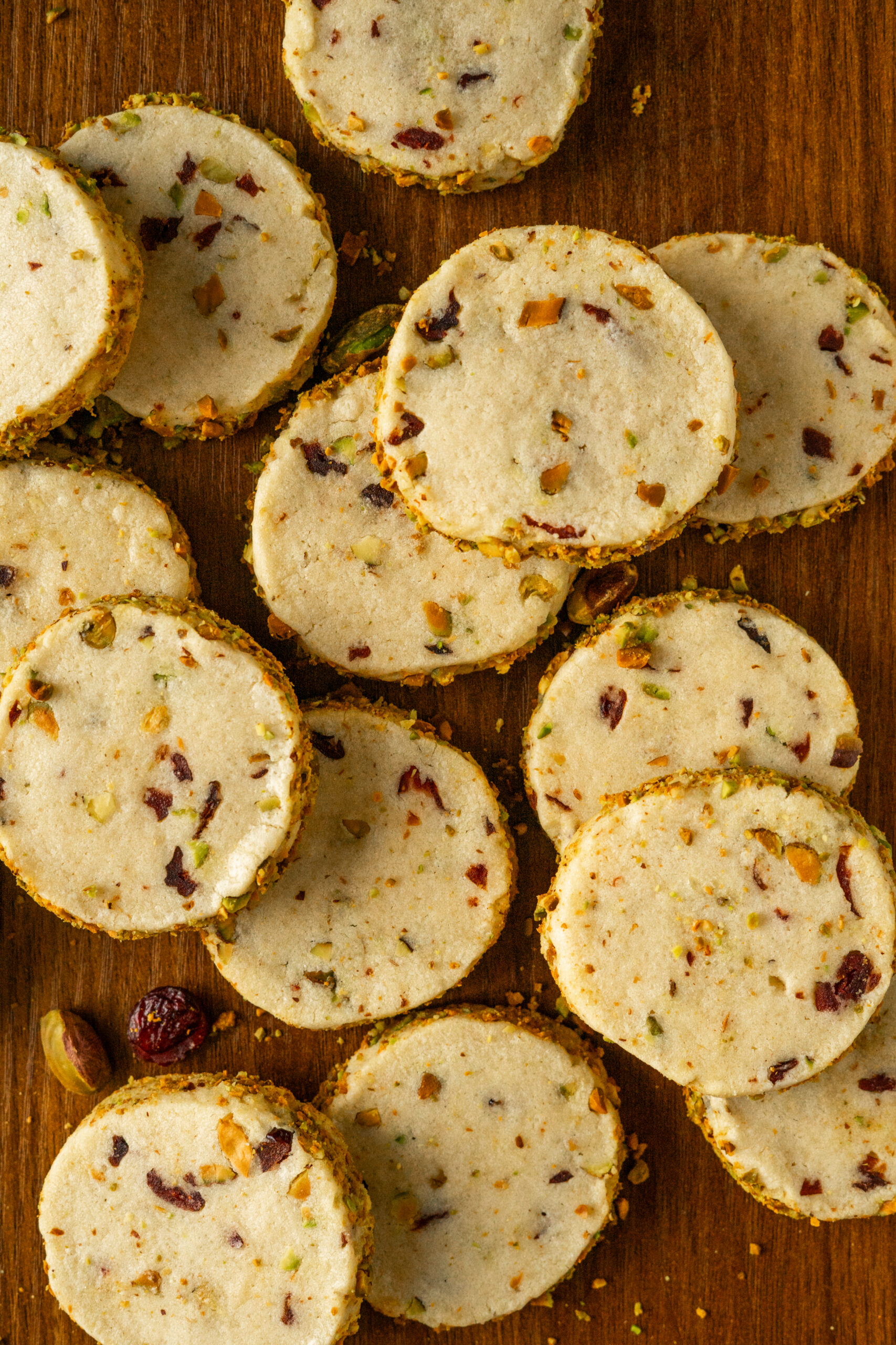 pistachio cranberry cookies scattered on wooden table.