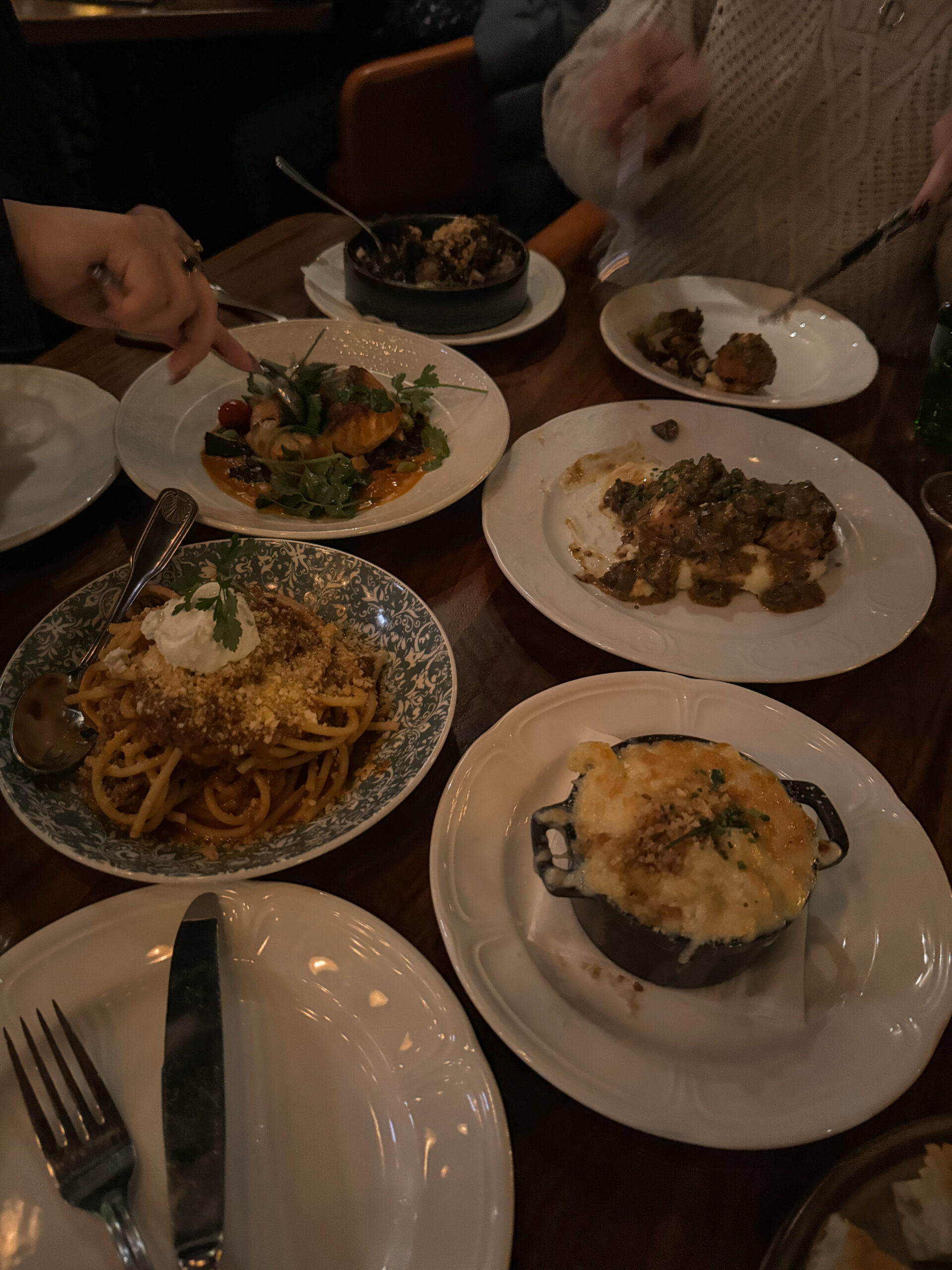 plates of pasta, chicken, and salmon on a table.