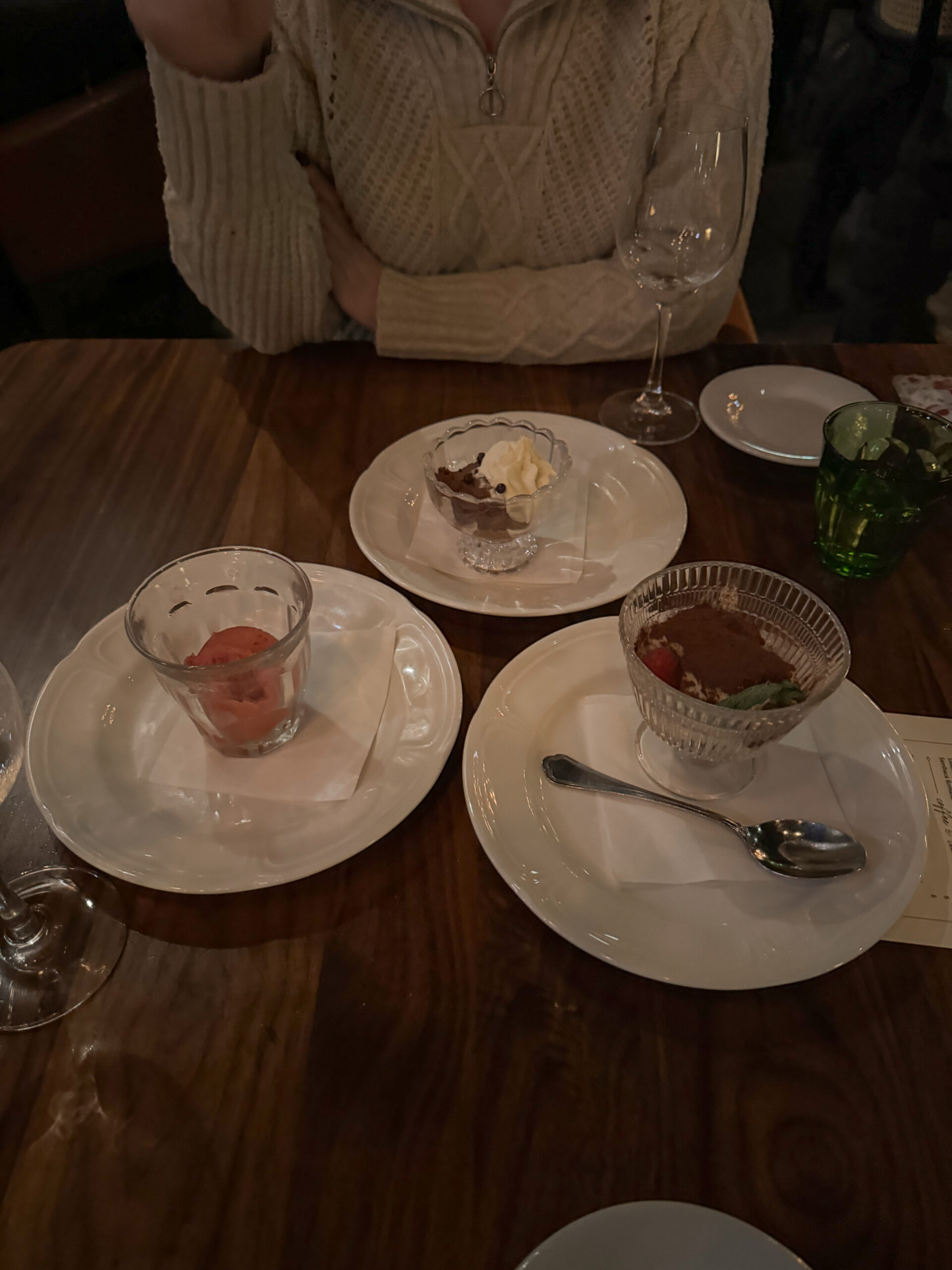 three desserts on white plates at table.