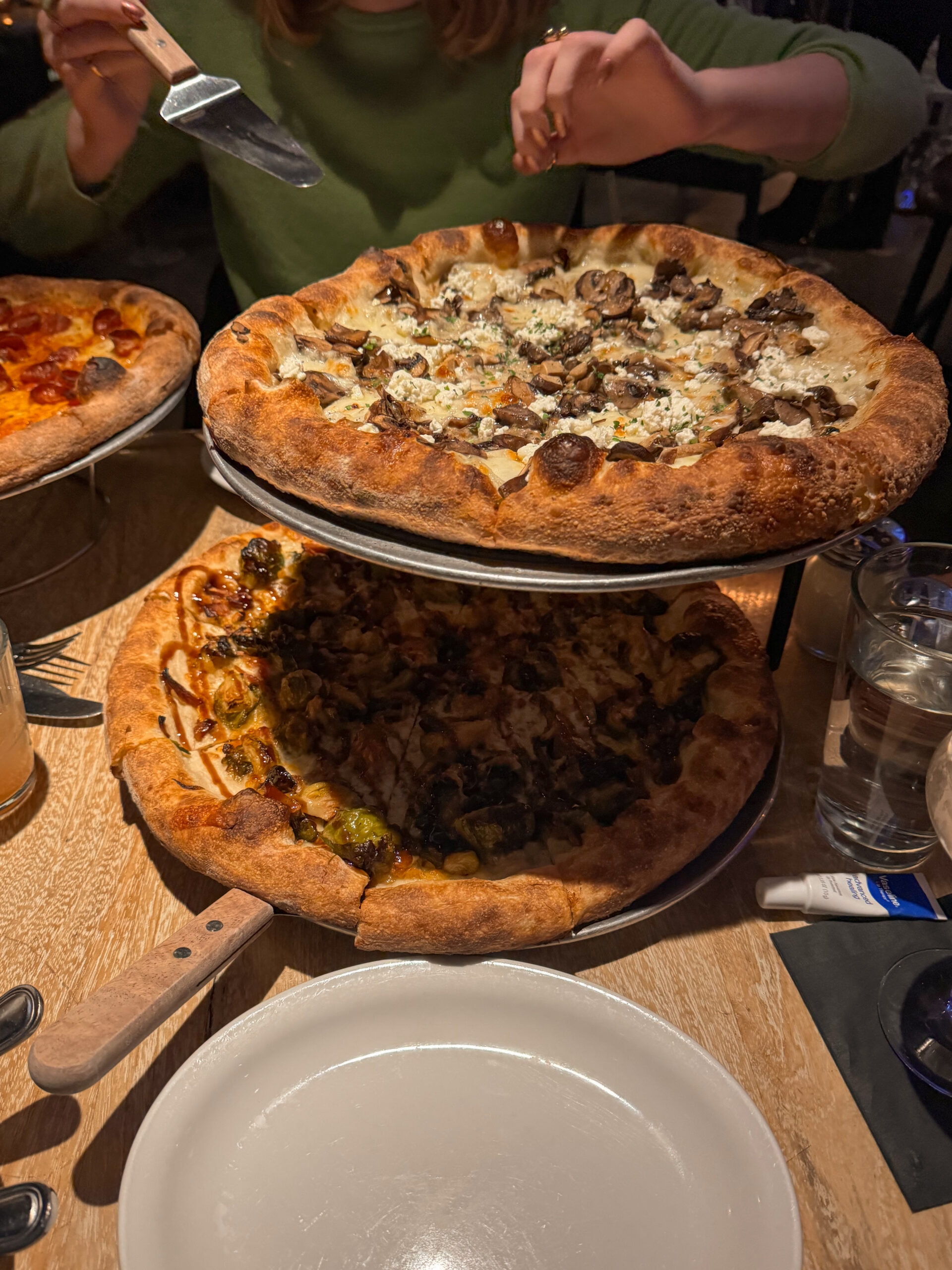 two pizzas stacked on metal tray.