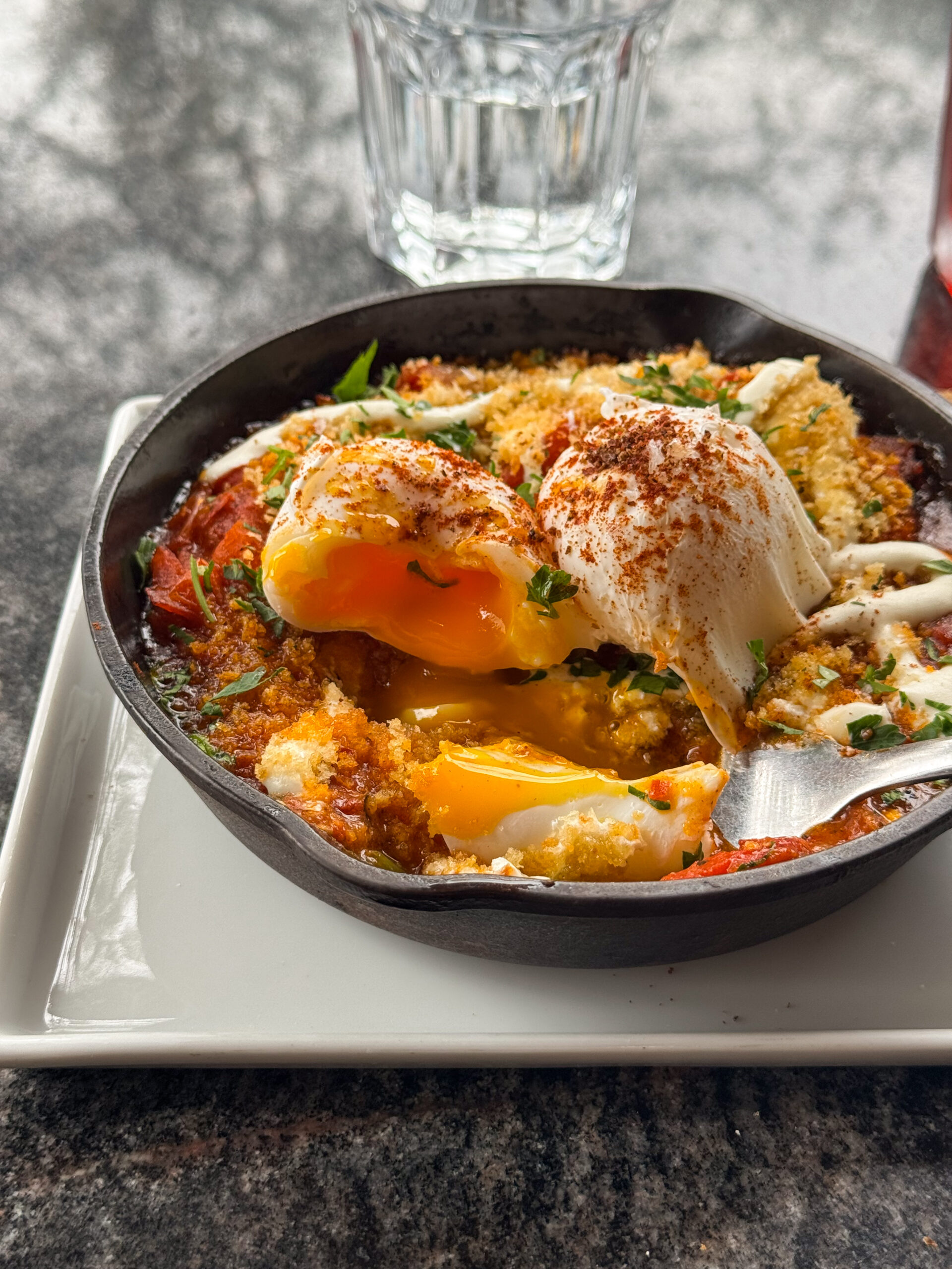 close up of shakshuka in cast iron pan on white plate.