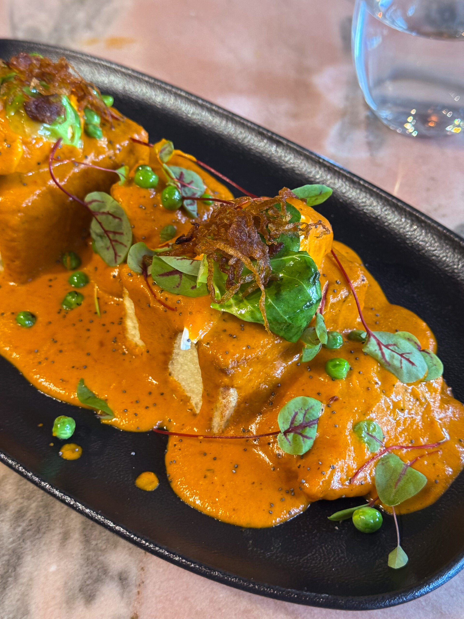 butter chicken eggs Benedict on black plate.